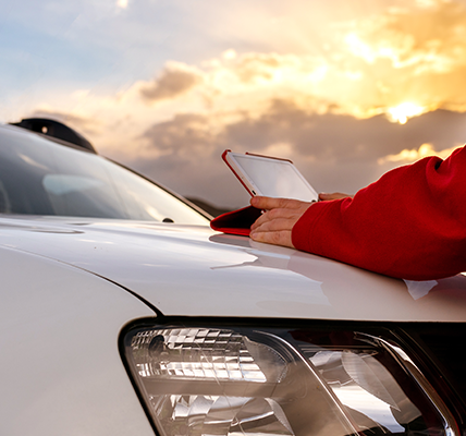 Person using a tablet sitting on a car